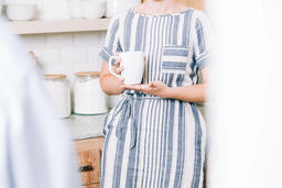 Woman Holding Cup of Coffee and having Conversation in the Kitchen  image 2