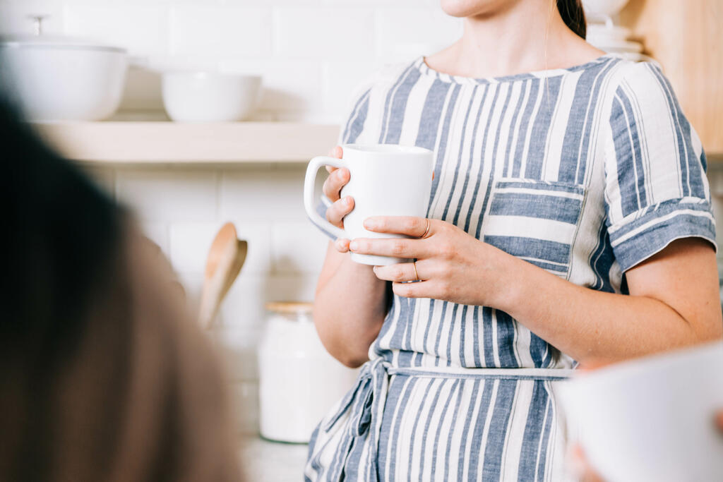 Woman Holding Cup of Coffee and having Conversation in the Kitchen large preview