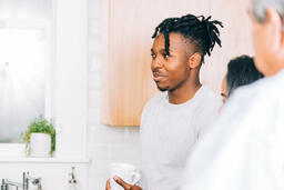 Man Holding Cup of Coffee and Having Conversation in the Kitchen  image 1