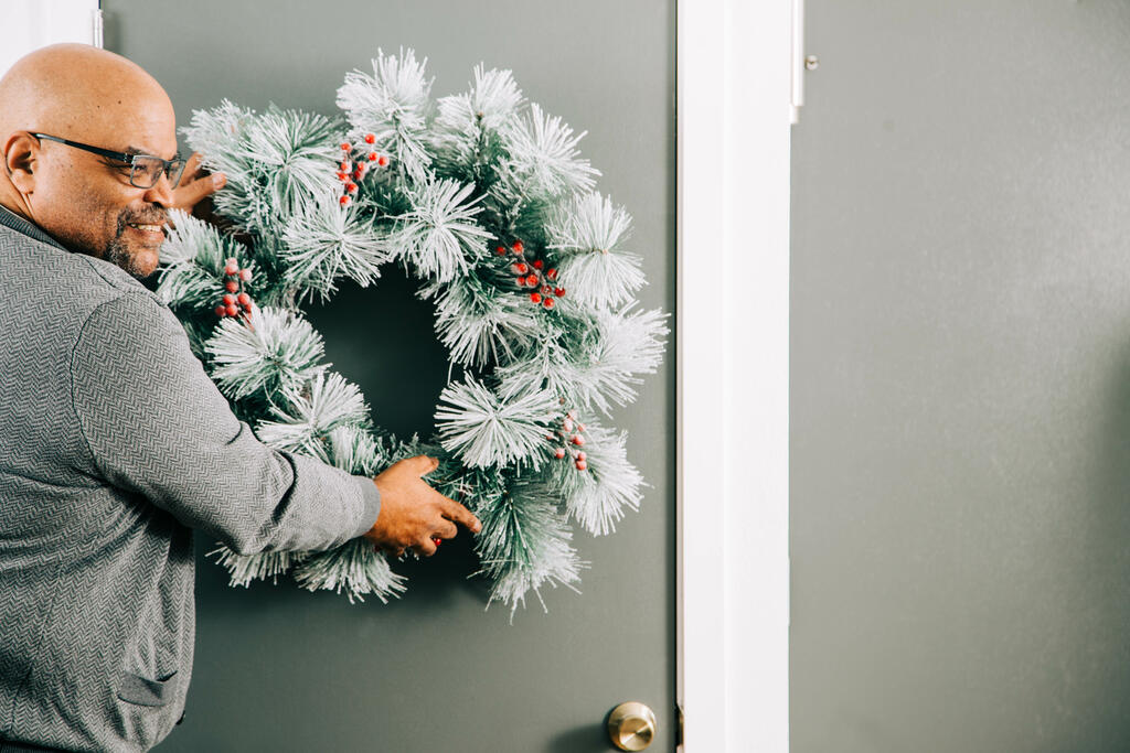Man Putting a Wreath on the Door for Christmas large preview