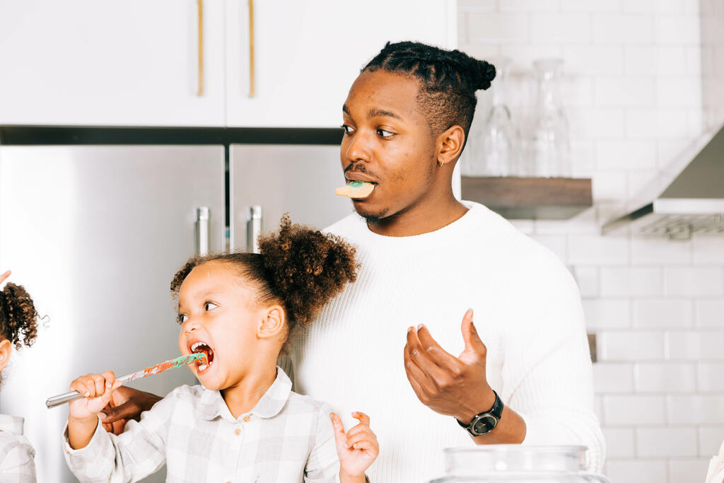 Father and Daughter Frosting and Eating Christmas Cookies Together large preview