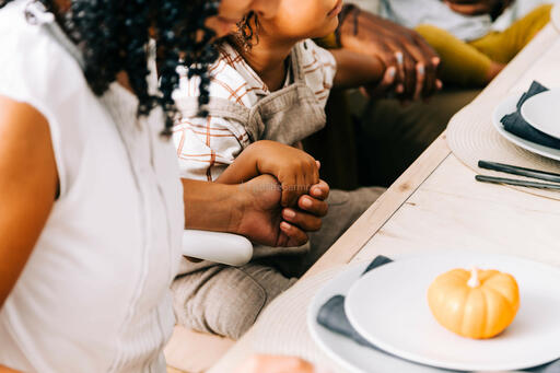 Woman and Child Holding Hand in Prayer Before the Thanksgiving Meal