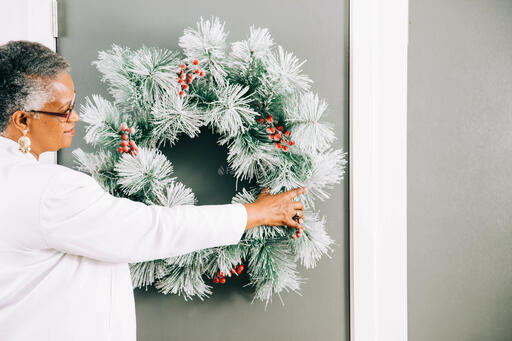 Woman Putting a Wreath on the Door for Christmas