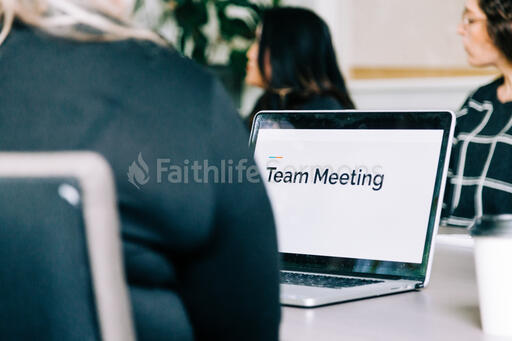 Woman Seated at Conference Table with Laptop Open During a Meeting