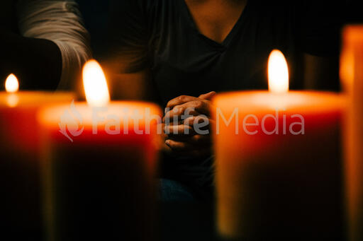 Woman Praying in Candle Lit Room