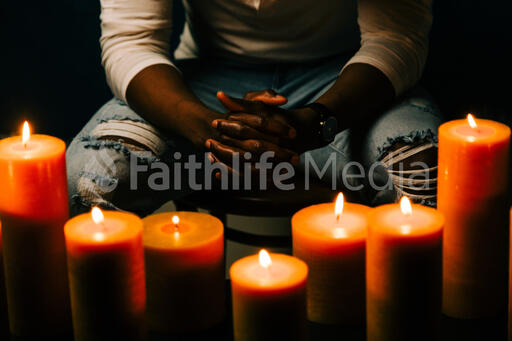 Man Praying in Candle Lit Room