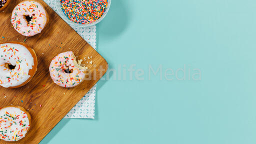 Frosted donuts on cutting block with sprinkles