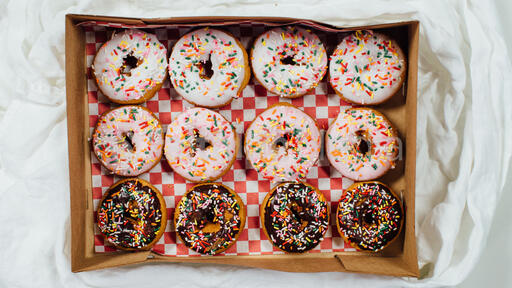 Box of frosted donuts with sprinkles