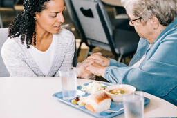 Volunteer Praying with an Elderly Woman at a Community Meal  image 3