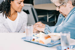 Volunteer Praying with an Elderly Woman at a Community Meal  image 5