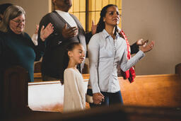 Mother and Daughter Holding Hands During Worship  image 3