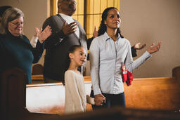 Mother and Daughter Holding Hands During Worship  image 2