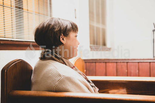 Woman Sitting in Pew and Taking a Sip of Coffee
