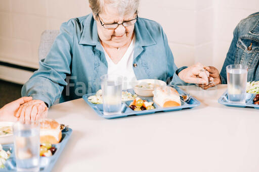 Elderly Woman Praying Before a Community Meal