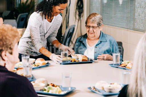 Volunteer Serving a Meal to a Woman at a Community Meal