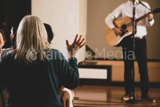 Elderly Woman with Hands Raised During Worship