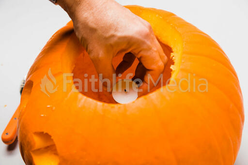 Hand Placing a Candle in a Jack-O-Lantern