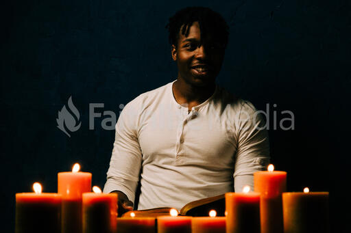 Man Reading Bible in Candle Lit Room