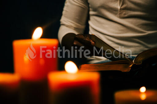 Man Reading Bible in Candle Lit Room