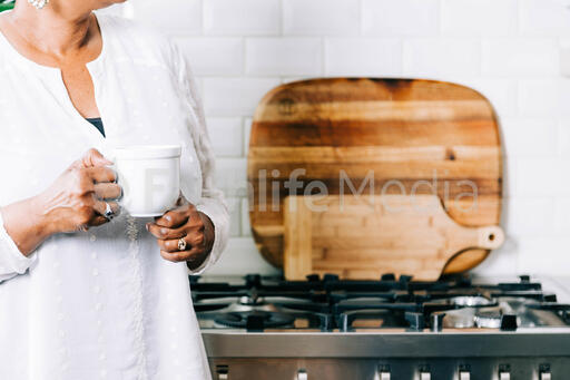 Woman Holding Cup of Coffee in the Kitchen
