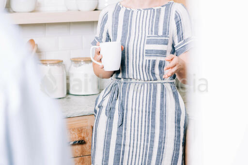 Woman Holding Cup of Coffee and having Conversation in the Kitchen