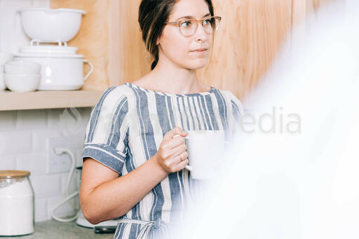 Woman Holding Cup of Coffee and having Conversation in the Kitchen