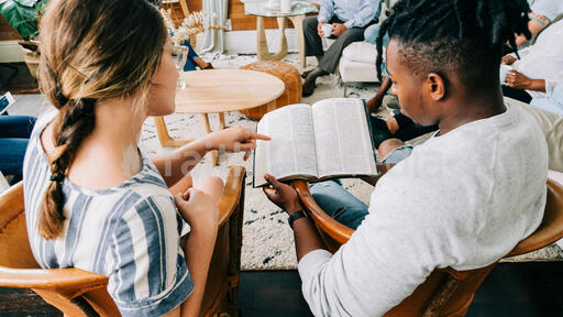 Woman Pointing out a Passage in Man's Bible at Small Group