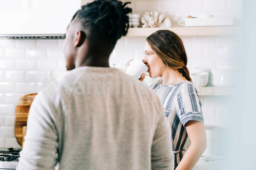 Woman Drinking Coffee with Small Group Members in the Kitchen