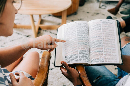 Woman Pointing out a Passage in Man's Bible at Small Group