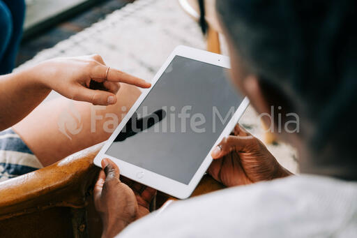 Woman Pointing at Man's iPad Screen