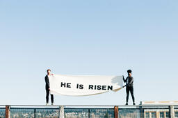 People Holding a He Is Risen Banner on a Rooftop  image 3