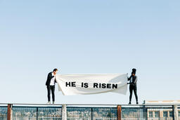 People Holding a He Is Risen Banner on a Rooftop  image 5