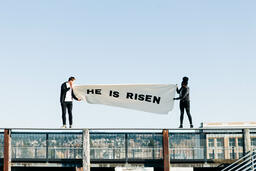 People Holding a He Is Risen Banner on a Rooftop  image 6