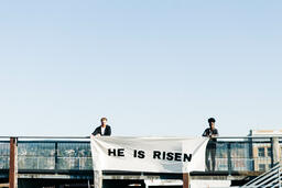 People Holding a He Is Risen Banner on a Rooftop  image 1