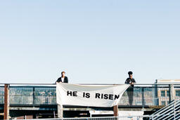 People Holding a He Is Risen Banner on a Rooftop  image 6