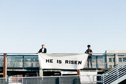 People Holding a He Is Risen Banner on a Rooftop  image 4