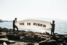 People Holding a He Is Risen Banner at the Beach  image 2