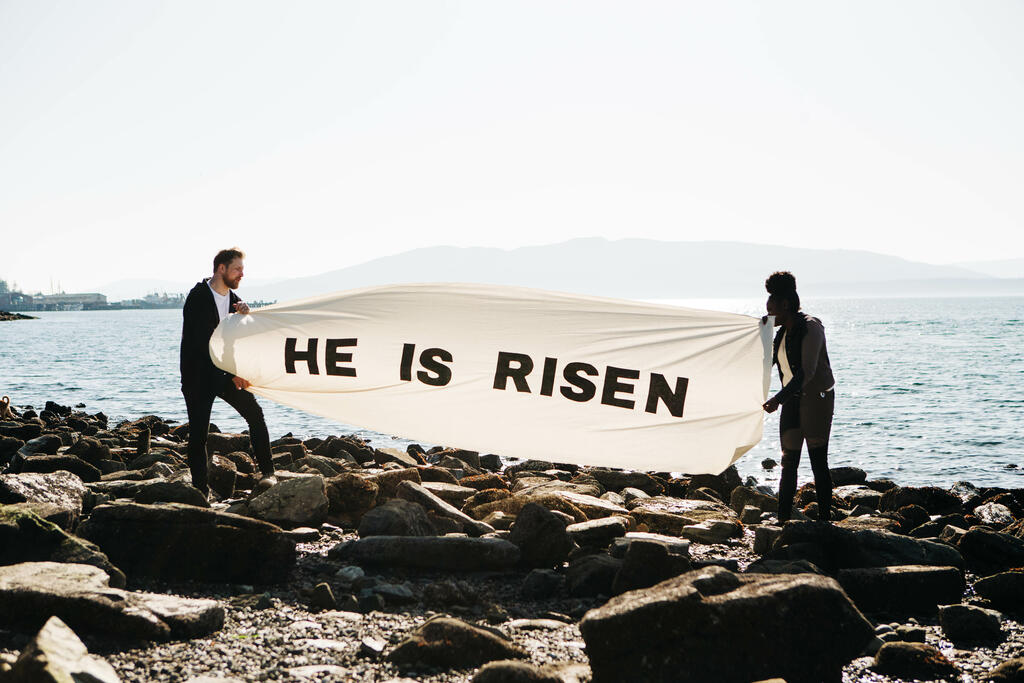 People Holding a He Is Risen Banner at the Beach large preview