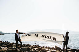 People Holding a He Is Risen Banner at the Beach  image 3