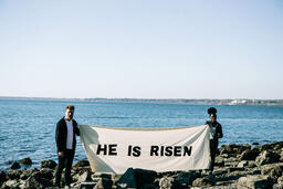 People Holding a He Is Risen Banner at the Beach  image 1