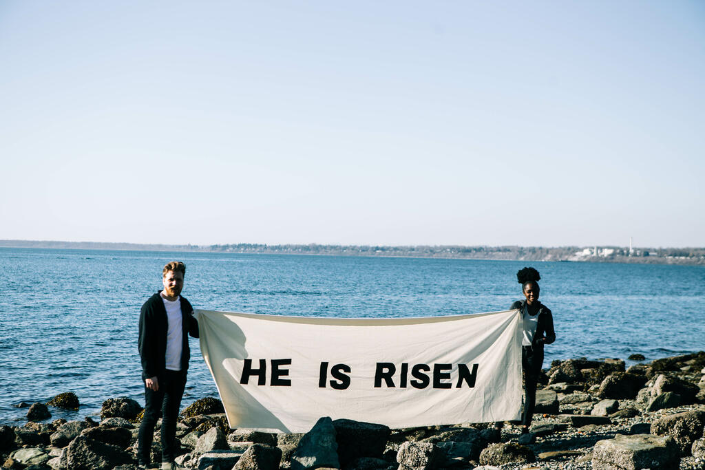 People Holding a He Is Risen Banner at the Beach large preview