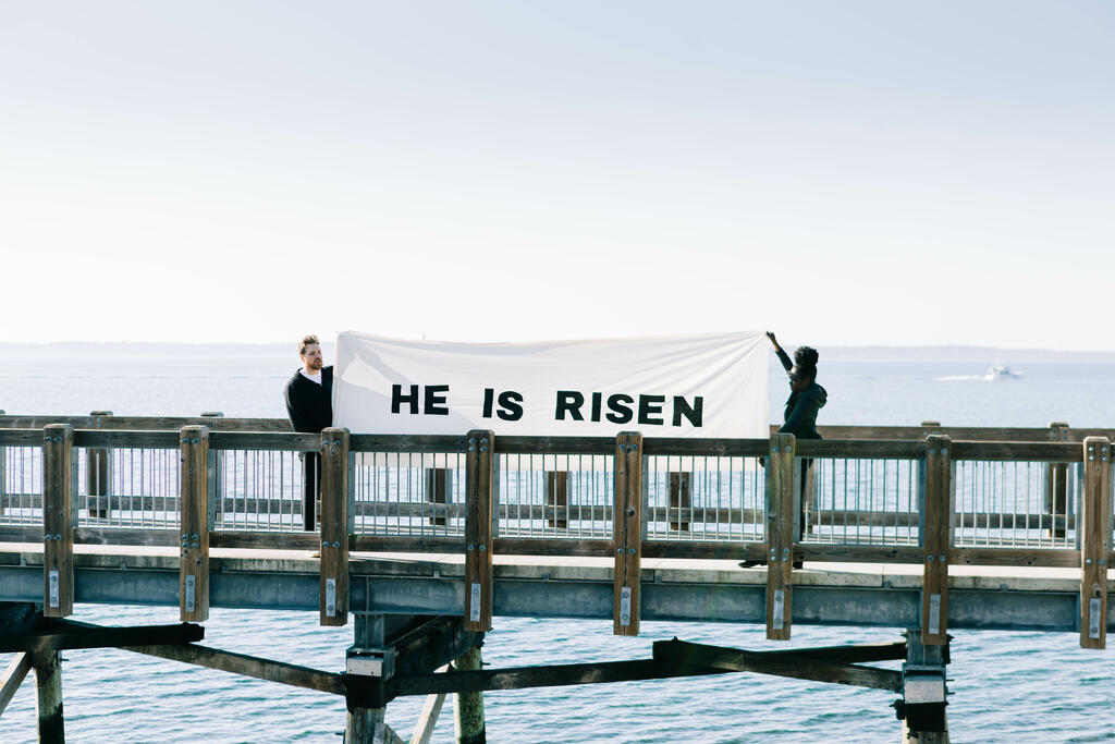 People Holding a He Is Risen Banner on a Boardwalk large preview