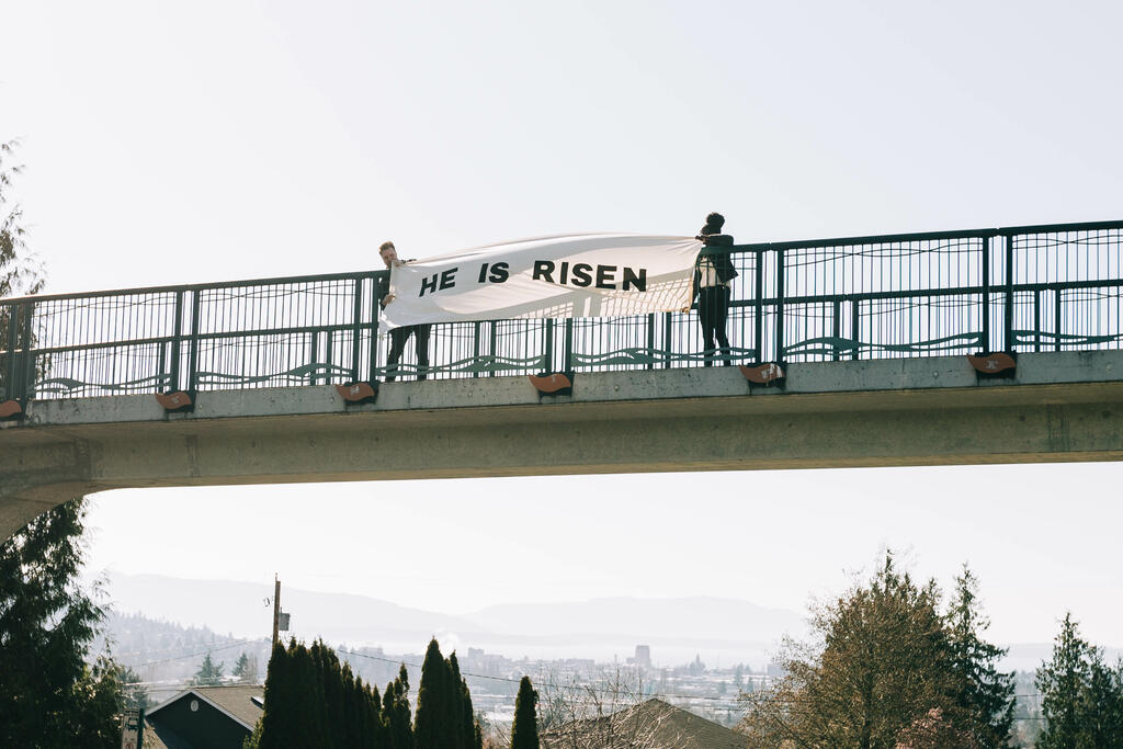 People Holding a He Is Risen Banner Over a Bridge large preview