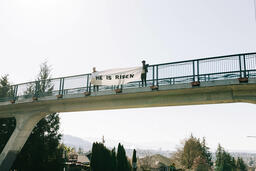 People Holding a He Is Risen Banner Over a Bridge  image 3