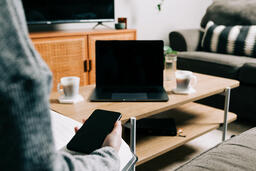 Woman Watching Church at Home on a Laptop While Holding Her Phone  image 1