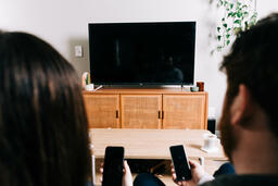 Couple in Living Room Looking at Their Phones in Front of a TV  image 3