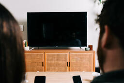 Couple in Living Room Looking at Their Phones in Front of a TV  image 1