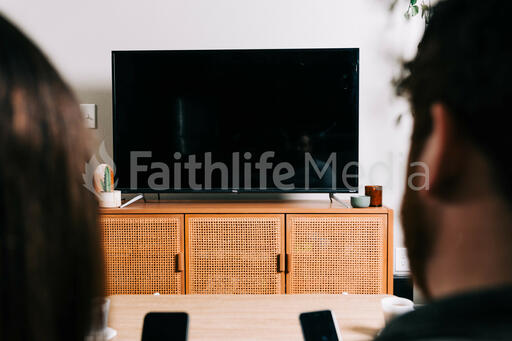 Couple in Living Room Looking at Their Phones in Front of a TV