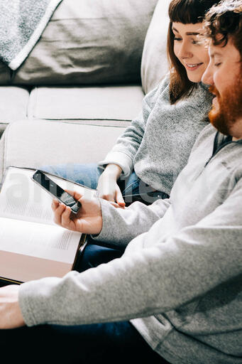 Couple Looking at a Smart Phone with an Open Bible
