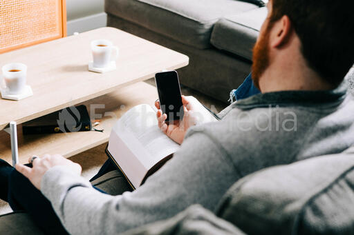 Man Holding His Phone and a Bible